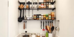 Wall-mounted kitchen rack with hanging utensils and spices in a small student kitchen